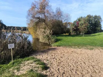 a sign in the sand next to a river at Chata U Bezedné in Velký Osek