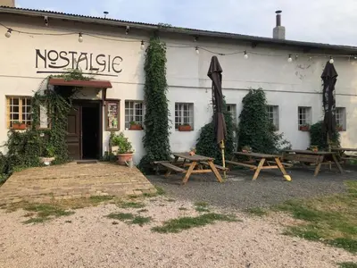 a white building with two picnic tables and an umbrella at Nostalgická myš in Kokořín