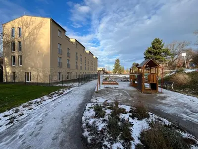 a snow covered street in front of a building at Charming studio near Prague Airport in Tuchoměřice