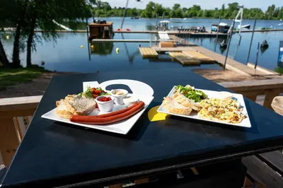 two plates of food on a table next to a body of water at House Boat s výhledem na Wake Port in Brandýs nad Labem-Stará Boleslav