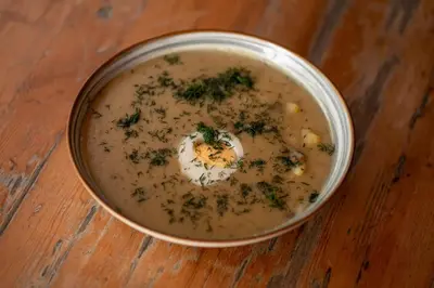 a bowl of soup with a poached egg and herbs at House Boat s výhledem na Wake Port in Brandýs nad Labem-Stará Boleslav