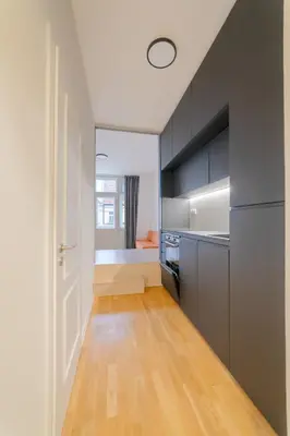 a kitchen with gray cabinets and a wooden floor at Chic Brick Suites in Historic Prague City Center by Rentez in Prague