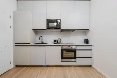 a kitchen with white cabinets and a microwave at Blueground Vinohrady close to Namesti Miru PRG-2 in Prague
