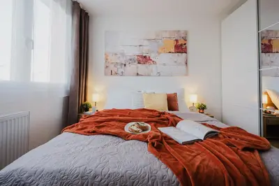 a bed with an orange blanket and two books on it at Prague Days - Two-Bedroom Apartment with Workspace and 200Mbps WiFi in Prague