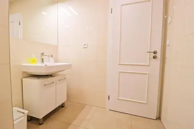 a white bathroom with a sink and a door at Spacious apartment in the center of Prague in Prague