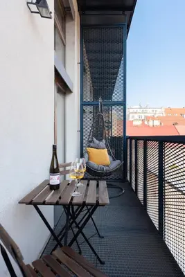 a patio with a hammock and a table and two glasses of wine at Deluxe apartments near center Prague in Prague