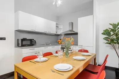a dining room table with red chairs and a kitchen at Deluxe apartments near center Prague in Prague