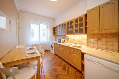 a kitchen with wooden cabinets and a table and a sink at 3 Bed Flat - Sleeps 12 - Wifi in Prague