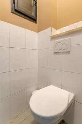 a bathroom with a white toilet and a window at Place of Grace - 1 min to National Theatre in Prague