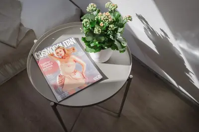 a glass table with a magazine and a vase of flowers at Spacious 4-Story Home with Sauna & Garden in Prague