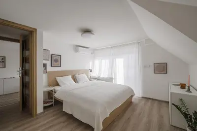 a white bedroom with a large bed and a window at Spacious 4-Story Home with Sauna & Garden in Prague