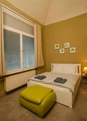 a bed with a green ottoman in a bedroom at Grand apartment near Dancing House in Prague