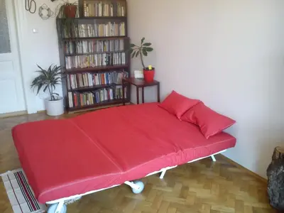 a red bed in a room with a book shelf at Rain Man's Apartment in Prague