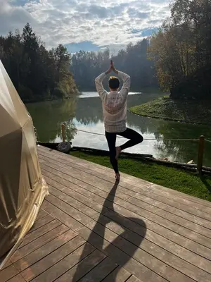 a person doing yoga on a deck near a lake at Glamp SunnyMoon in Sudoměř