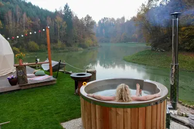 a woman laying in a hot tub next to a lake at Glamp SunnyMoon in Sudoměř