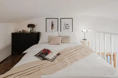 a bedroom with a large white bed with two pictures on the wall at Prague Days - Loft-style One-bedroom Apartment in the City Center in Prague