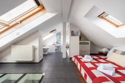a attic bedroom with a bed and a bathroom at Charming Prague Apartment in Vrovice with Roof Terrace in Prague