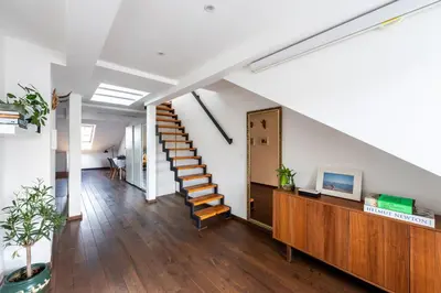 a staircase in a living room with white walls and wooden floors at Charming Prague Apartment in Vrovice with Roof Terrace in Prague