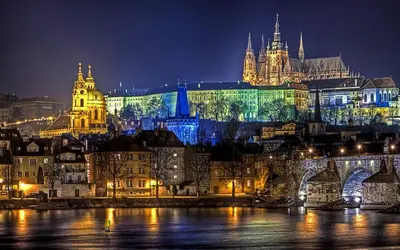 a city lit up at night with a castle at Golden Dog Suite in Prague