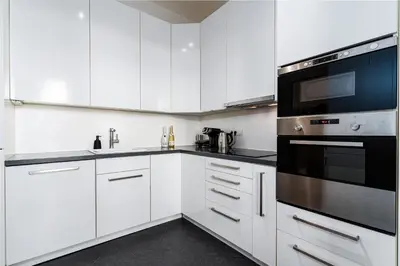 a kitchen with white cabinets and a black appliance at Golden Dog Suite in Prague