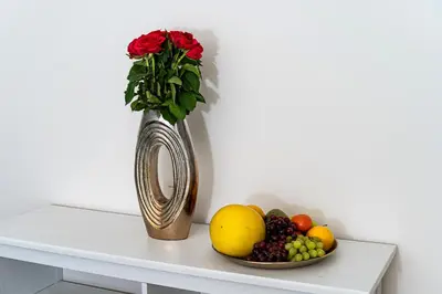 a vase with a bouquet of roses next to a plate of fruit at Golden Dog Suite in Prague