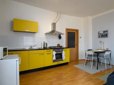 a kitchen with yellow cabinets and a table in it at Comfortable apartment in Prague 8 - Libeň in Prague