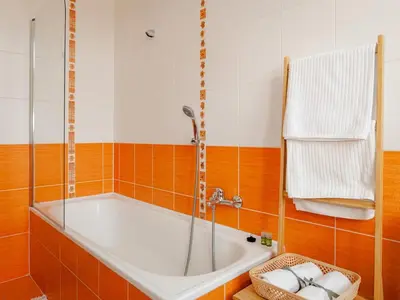 a bath tub in a bathroom with orange and white tiles at Comfortable apartment in Prague 8 - Libeň in Prague