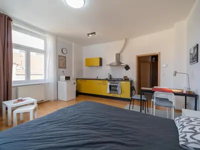 a bedroom with a bed and a kitchen with yellow cabinets at Comfortable apartment in Prague 8 - Libeň in Prague