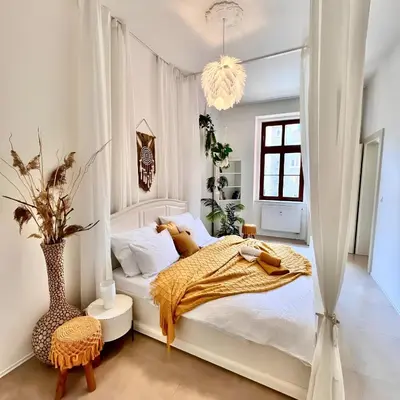 a white bedroom with a bed and a chandelier at Central Cozy Gateway in Prague