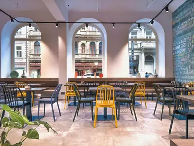 a restaurant with tables and chairs and windows at EA Hotel Moment Self Check-In in Prague