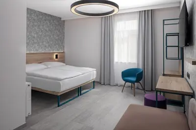 a bedroom with a bed and a blue chair at EA Hotel Moment Self Check-In in Prague