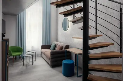 a living room with a couch and a spiral staircase at EA Hotel Moment Self Check-In in Prague