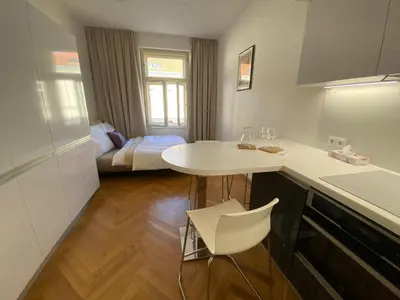 a kitchen with a white counter and a table and a bed at Modern Apartments Letna in Prague