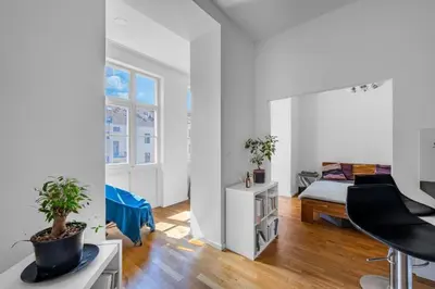 a white room with a bed and a table with a plant at Great apartment in the hype neighborhood in Prague