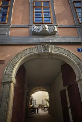 an archway leading into a building with tables at Queen Bee apartments in Prague