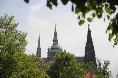 two towers of a building with trees in the foreground at Riverside Hideout in Prague
