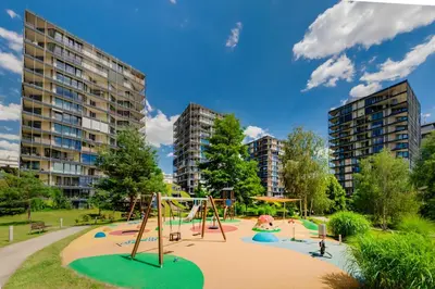 a playground in a park with tall buildings at Prostorný byt 3kk s krásnou terasou a vnitřním parkem in Prague