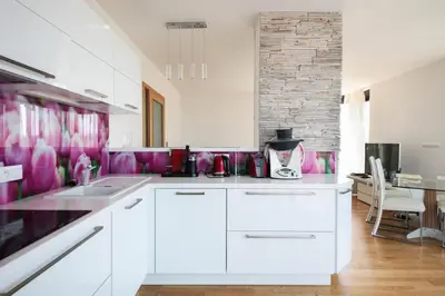 a kitchen with white cabinets and pink wallpaper at Prostorný byt 3kk s krásnou terasou a vnitřním parkem in Prague