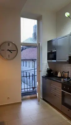 a kitchen with a clock on the wall and a window at Premium Apt - Free Massages from Physiotherapists in Prague