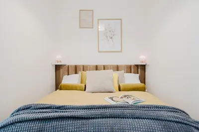 a bed with a blue blanket and two books on it at Prague Days - Apartments with Garage and Balcony Near City Center in Prague
