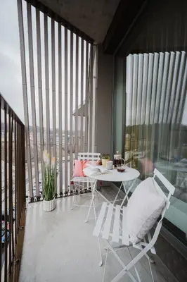 a white table and chairs on a balcony with windows at Prague Days - Apartments with Garage and Balcony Near City Center in Prague