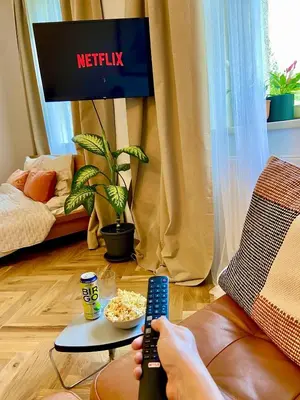 a person holding a remote control in a living room at Quiet Warm studio, 5 min to Metro A, airport link, fast Wi-Fi in Prague