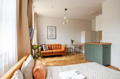 a living room with a couch and a kitchen at Quiet Warm studio, 5 min to Metro A, airport link, fast Wi-Fi in Prague