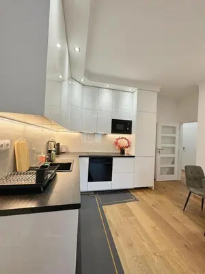 a kitchen with white cabinets and a black counter top at Cozy Nest Home in Prague