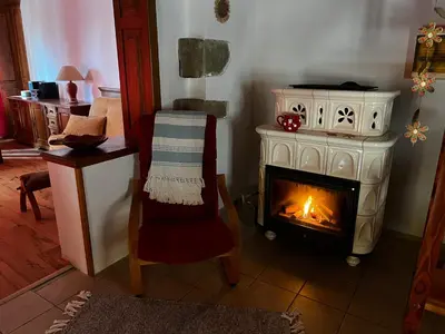 a living room with a stove and a chair and a fireplace at Chalupa Na Vyhlídce in Sudoměř