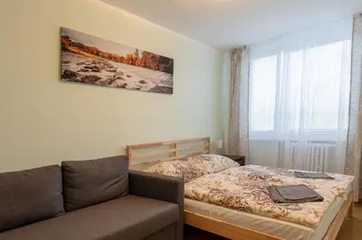 a bedroom with a bed and a couch and a window at Large apartment Prosek - Your second home! in Prague