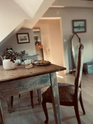 a wooden table with a plate of food and a chair at Penzion Patina House Barevný Svět in Mníšek pod Brdy