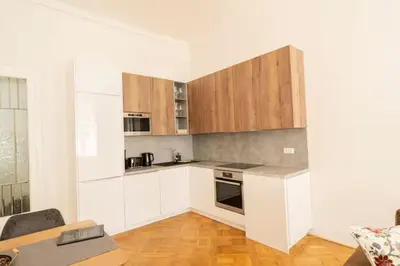 a white kitchen with wooden cabinets and a table at LUXURY RESIDENCE APARTMENTS in VÁCLAVSKÉ NÁMĚSTÍ in Prague