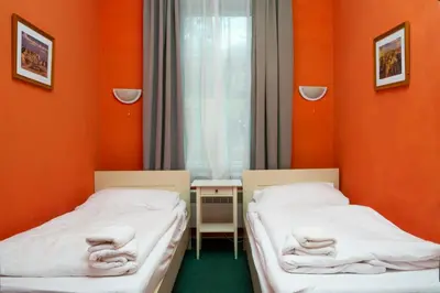 two beds in a room with orange walls at Hotelové Pokoje Kolčavka in Prague