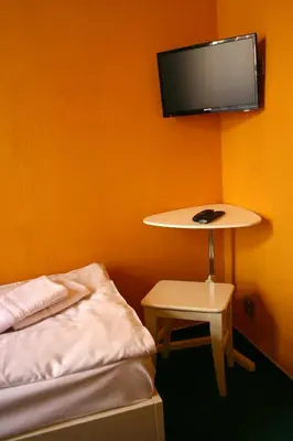a room with a bed and a table and a tv at Hotelové Pokoje Kolčavka in Prague